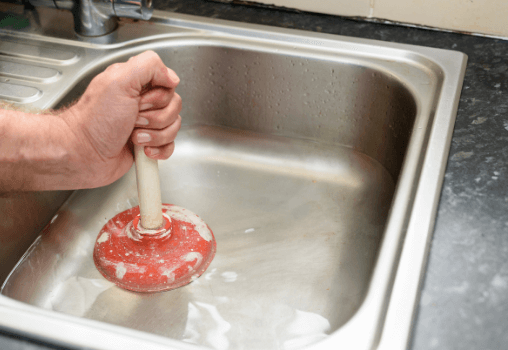Plunger being used in a metal kitchen sink